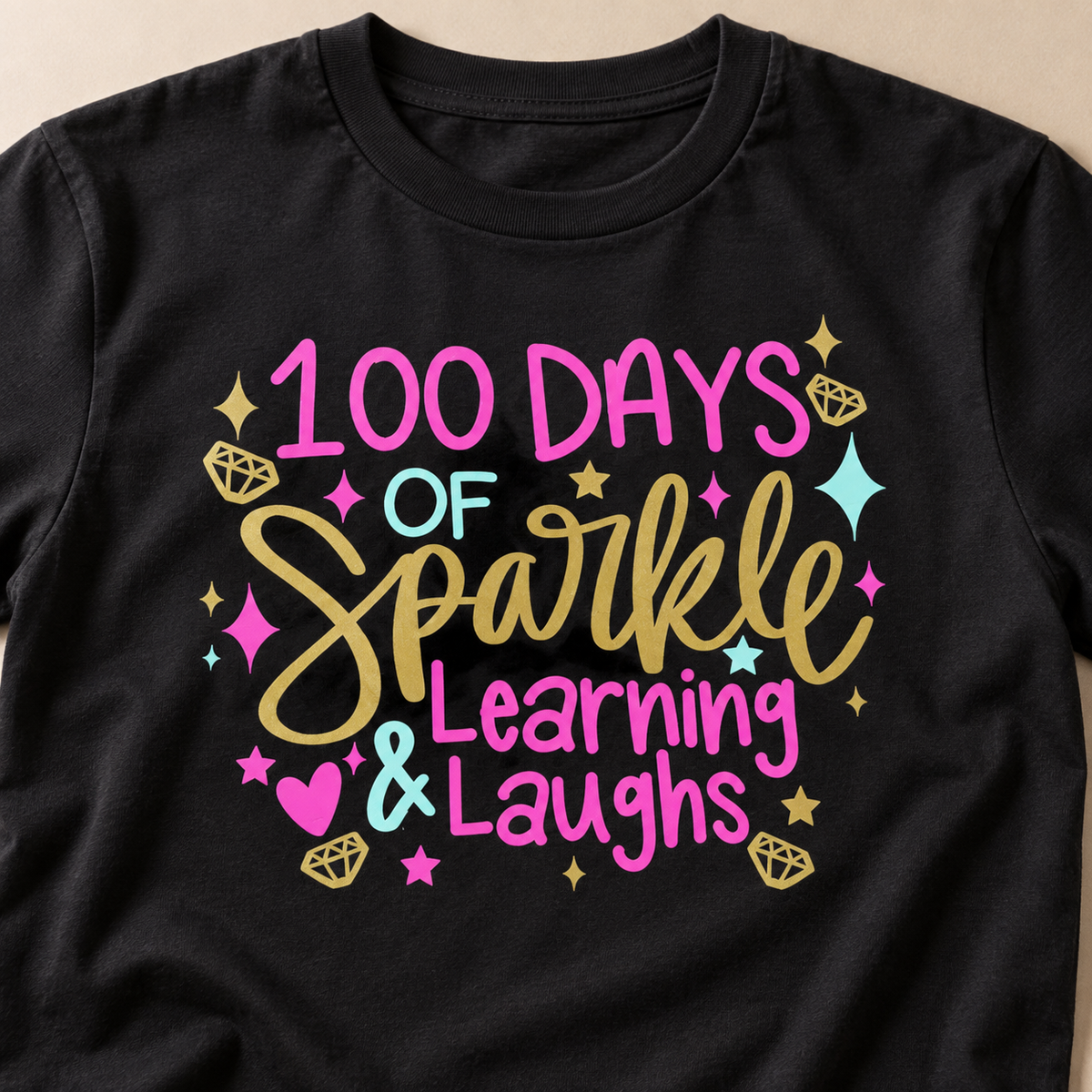 Close-up of the colorful 100 Days of Sparkle Learning and Laughs design on a black tee
